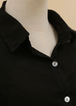 Black shirt with collar and buttons on a mannequin against a beige background