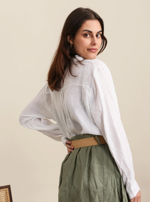Woman wearing a white blouse and green skirt against a beige background