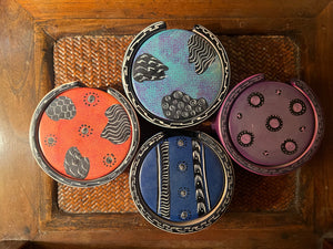 Four round containers with colorful lids on a woven surface