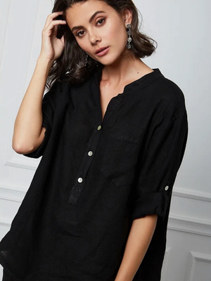 Woman wearing a black henley shirt with a neutral background