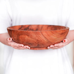 Person holding a wooden bowl against a white background