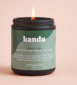 Kandu balsam sage candle with a lit wick on a beige background