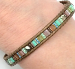 Beaded bracelet with multicolored beads on a wrist against a neutral background