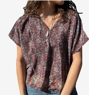 Person wearing a patterned blouse with short sleeves on a white background