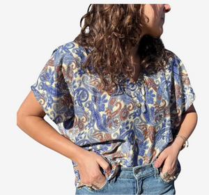Person wearing a blue patterned shirt with a plain white background.