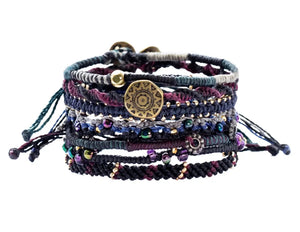 Multistrand bracelet with beads and a gold coin charm on a white background