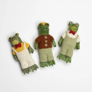 Three knitted frog toys dressed in different outfits on a white background