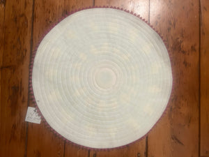 Bottom view of round woven mat on a wooden floor