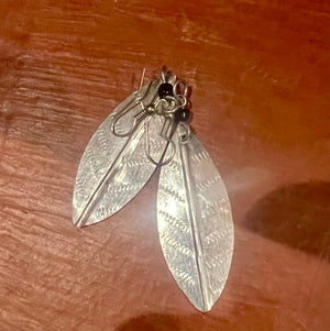 Silver leaf-shaped earrings on a wooden surface