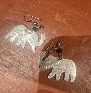Silver elephant earrings on a wooden surface
