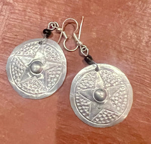 Silver star-shaped earrings on a wooden surface