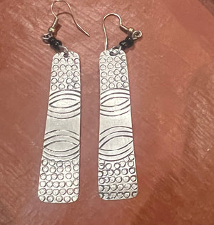 Silver patterned earrings on a wooden surface