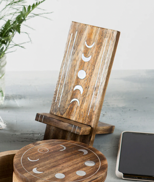 Wooden phone stand with moon phase design on a light surface.