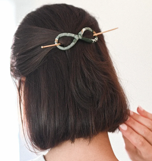 Person with a slide and stick hair accessory on a plain background