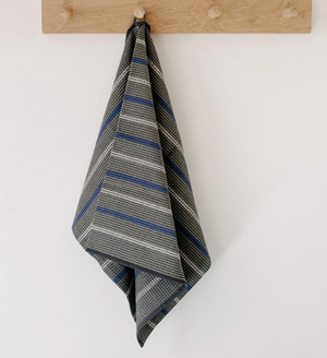 Striped grey towel hanging on a wooden rack against a white wall