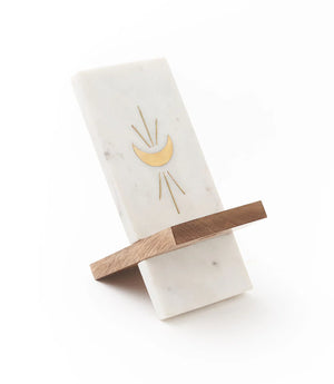 Marble and wood phone stand with gold moon design on a white background