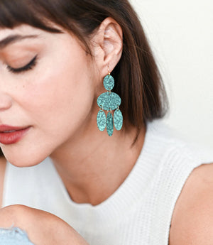 Close-up of a woman wearing turquoise earrings with a plain background