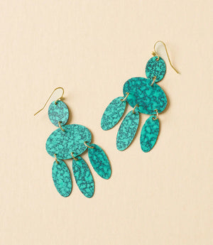 Turquoise earrings with gold accents on a beige background
