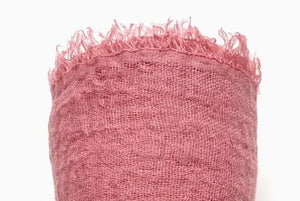 Pink textured fabric with frayed edges on a white background