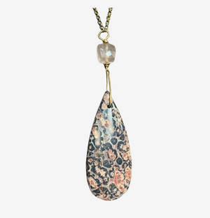 Teardrop-shaped pendant with floral pattern on a white background