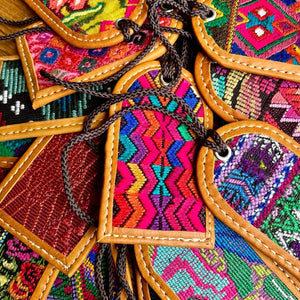 Colorful embroidered fabric luggage tags with geometric patterns and brown leather accents.