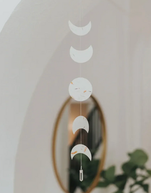 Decorative hanging with moon phase design in front of a mirror