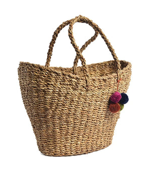Woven straw tote bag with colorful pom-poms on a white background