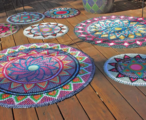 Colorful crocheted mandala rugs on a wooden floor