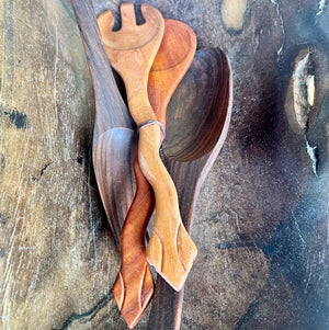 Wooden utensils with snake shaped handles on a textured surface