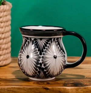 Black and white patterned mug on a wooden surface with a green background