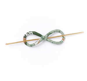 Green patterned hairpin with a wooden stick on a white background