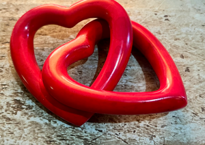 Red heart-shaped object on a wooden surface