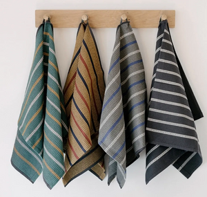 Set of four striped towels hanging on a wooden rack against a white wall.