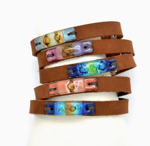Brown leather bracelet with colorful resin accents on a white background