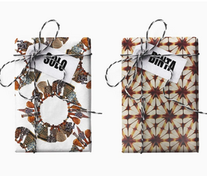 Two boxes wrapped in patterned  wrapping paper with twine bow on a white background