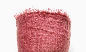 Close-up of a pink fabric with frayed edges on a white background