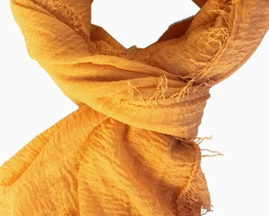 Close-up of a yellow scarf with frayed edges on a white background