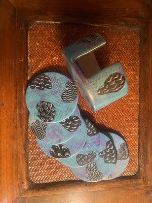 Set of light blue coasters and holder with a decorative pattern on a woven surface
