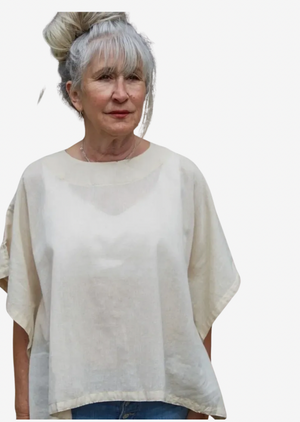 Woman wearing an off white boxy top against a white background