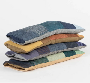Stack of patchwork pillows in various colors on a white background