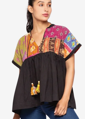 Woman wearing a colorful patterned top with a black base on a white background