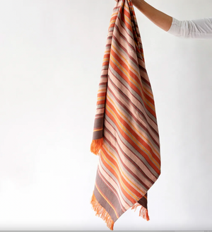 Striped scarf with orange and brown colors held by a person on a white background