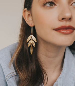 Close-up of a woman wearing gold earrings with a neutral background