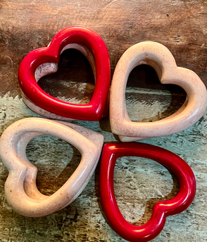 Two red and two beige heart-shaped ceramic items on a wooden surface