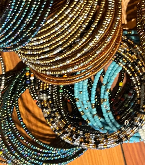 Stack of beaded bracelets in various colors on a wooden surface