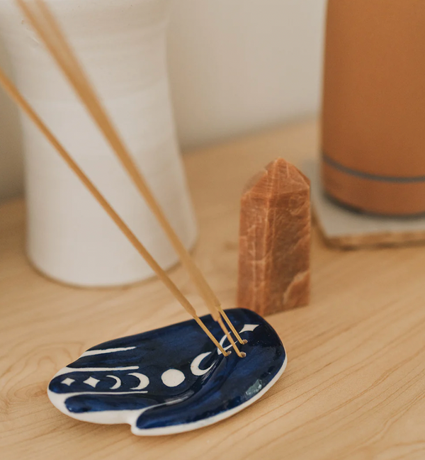 Incense sticks on a blue ceramic holder with a brown crystal in the background.