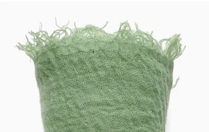 Close-up of green textured fabric with frayed edges on a white background