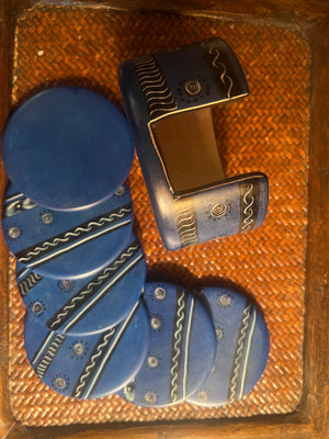 Set of blue coasters and holder with a decorative pattern on a woven surface