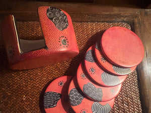 Set of orange coasters and holder with a decorative pattern on a woven surface