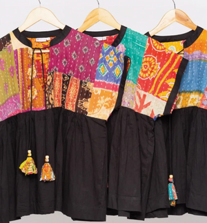 Two colorful dresses with black skirts on hangers against a white background